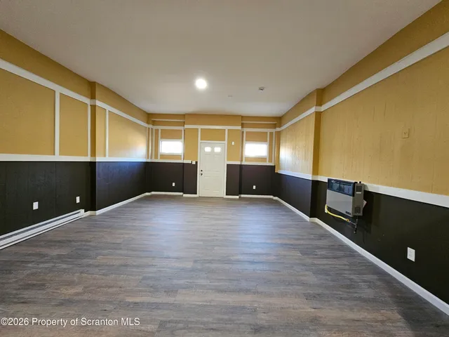 a view of an empty room with kitchen natural and wooden floor