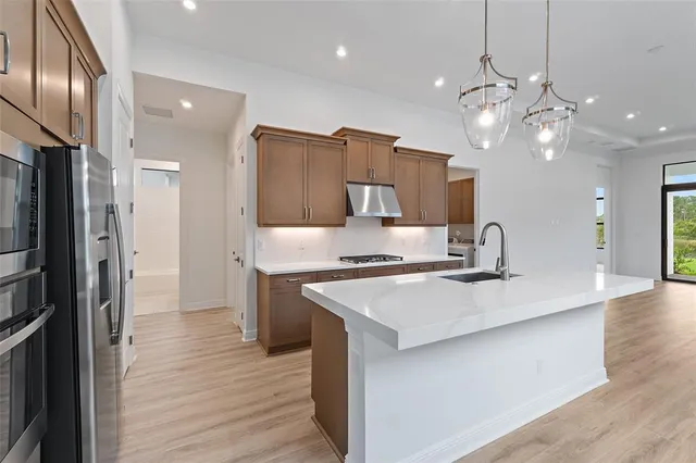 a kitchen with kitchen island a sink stainless steel appliances and wooden floor