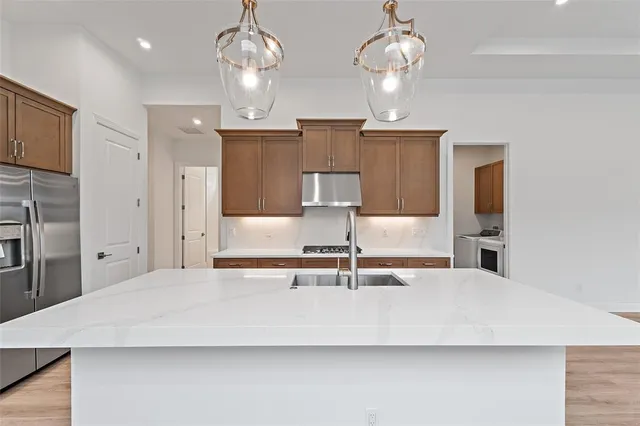 a large kitchen with kitchen island granite countertop a sink and refrigerator