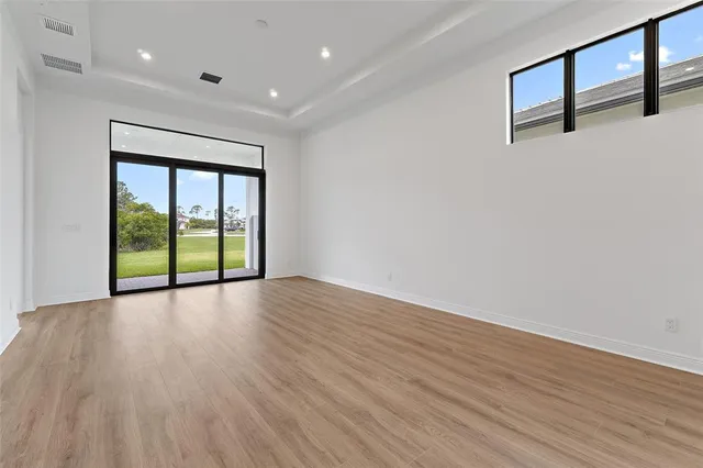 a view of empty room with wooden floor and fan