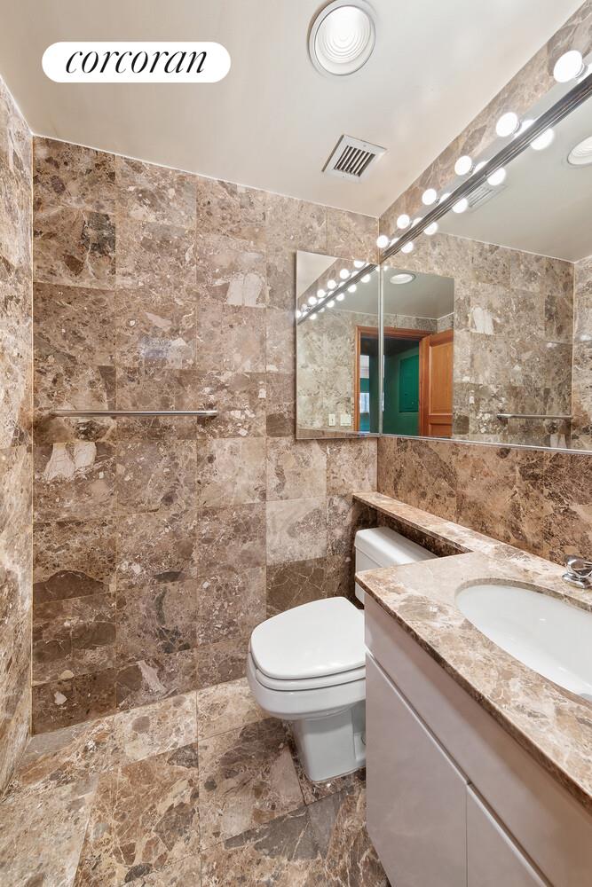 157 East 74th Street, Unit 9B Manhattan, NY 10021 - Photo 8 of 9 a bathroom with a granite countertop sink a toilet and mirror
