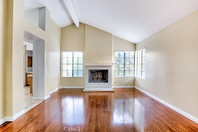 a view of an empty room with window and wooden floor