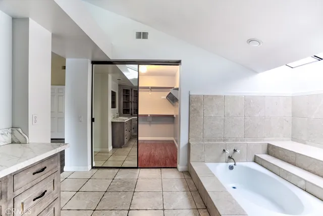 a large white kitchen with a sink a window and stainless steel appliances
