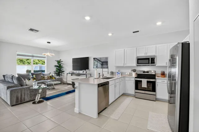 a kitchen with stainless steel appliances a refrigerator sink and white cabinets