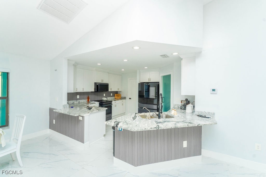 3613 39th Street Southwest Lehigh Acres, FL 33976 - Photo 16 of 46 a kitchen with stainless steel appliances a sink stove and cabinets