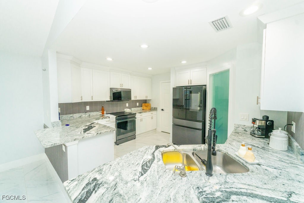 3613 39th Street Southwest Lehigh Acres, FL 33976 - Photo 19 of 46 a kitchen with stainless steel appliances granite countertop a sink a stove and a refrigerator