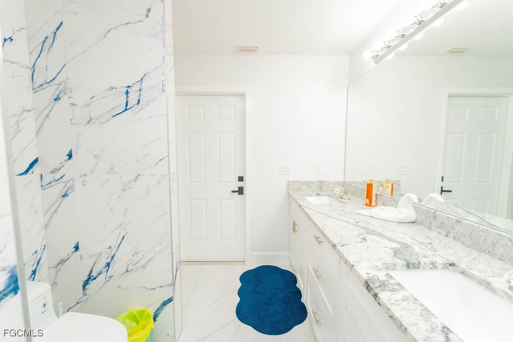 3613 39th Street Southwest Lehigh Acres, FL 33976 - Photo 38 of 46 a bathroom with a granite countertop sink a toilet and shower