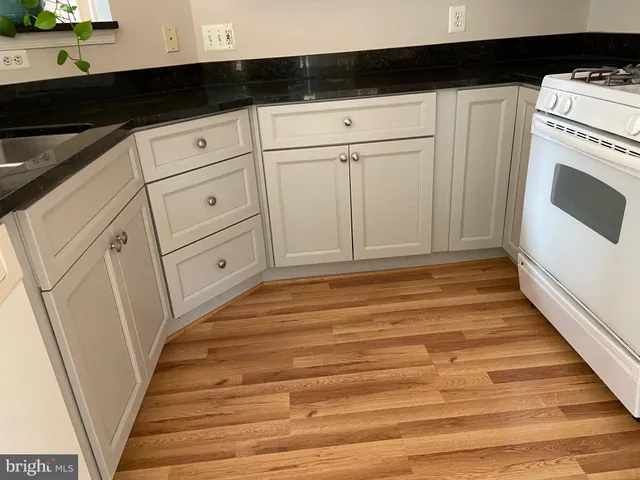 a kitchen with granite countertop white cabinets and white appliances