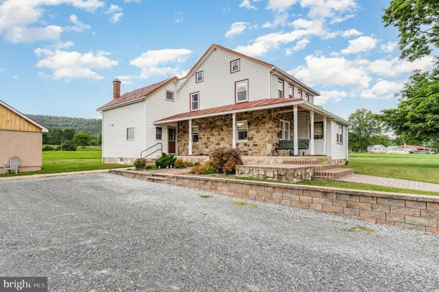 a view of a white house with a big yard and large trees