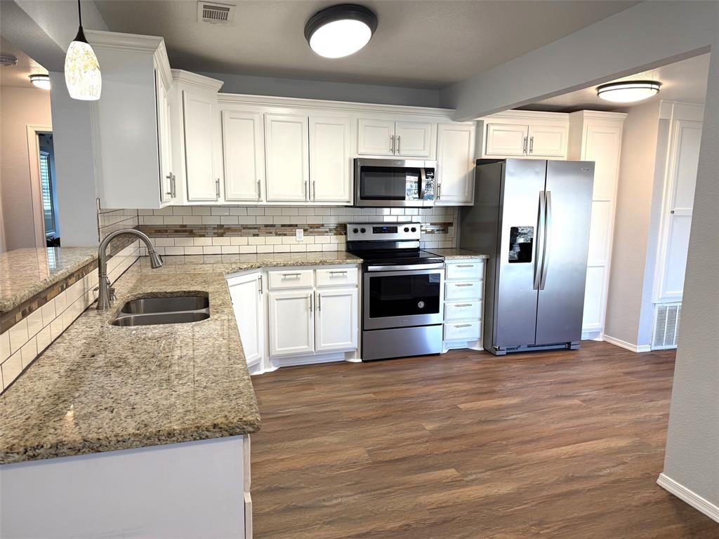 1826 North Woods Street Sherman, TX 75092 - Photo 8 of 29 a kitchen with stainless steel appliances granite countertop a sink a stove a refrigerator with grey cabinets