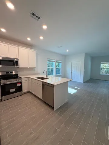 a large kitchen with stainless steel appliances a large counter top a stove and a refrigerator