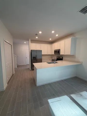 a large white kitchen with kitchen island sink refrigerator and white cabinets