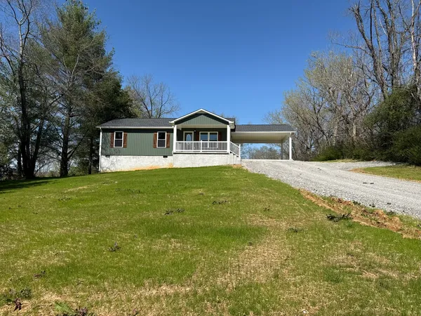 a front view of house with yard and trees in the background