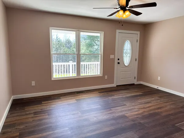 a view of an empty room with wooden floor and a window