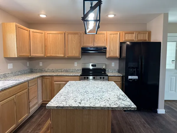 a kitchen with stainless steel appliances granite countertop a refrigerator a stove a sink and a microwave