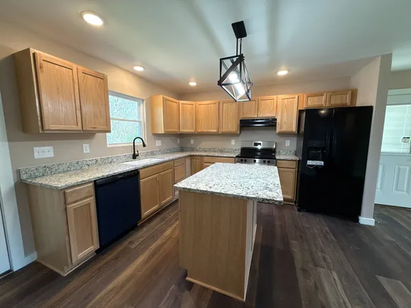 a kitchen with a refrigerator a sink and wooden floor