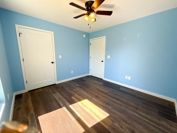 a view of a room with wooden floor and a ceiling fan