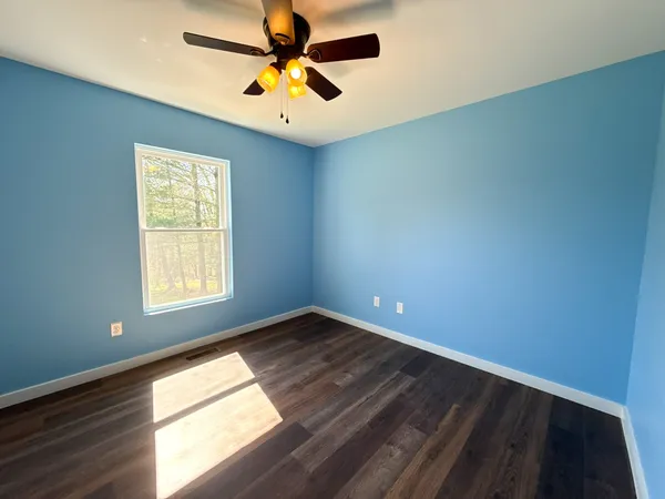 an empty room with a window and a fan