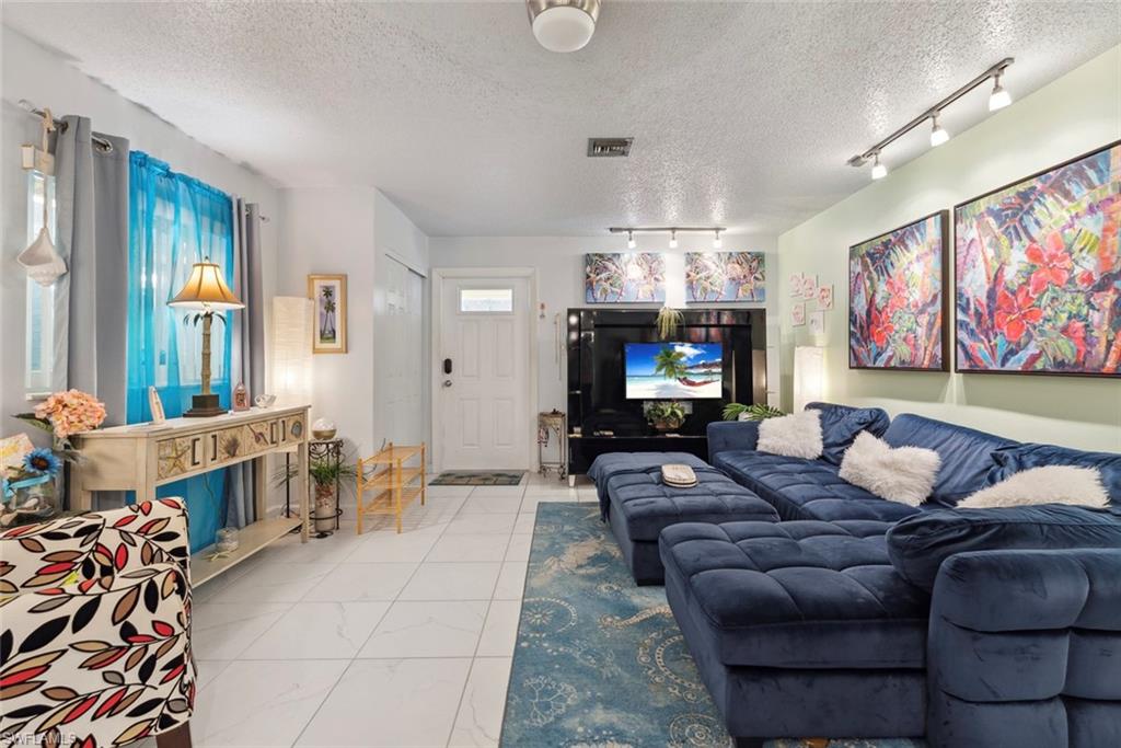 126 Harrison Road, Unit M3 Naples, FL 34112 - Photo 6 of 48 Living room featuring track lighting, visible vents, marble finish floor, and a textured ceiling