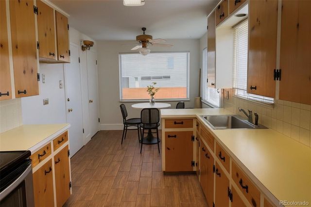 a kitchen with a sink a stove a refrigerator and a dining table with wooden floor