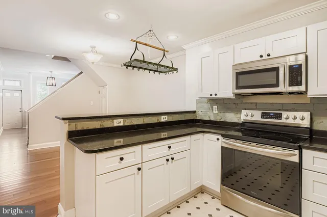 a kitchen with granite countertop white cabinets and stainless steel appliances