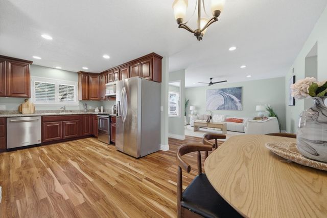 a kitchen with stainless steel appliances kitchen island granite countertop a refrigerator a stove and a sink with cabinets