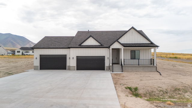 1214 Highline Road, Unit 208 Lake Point, UT 84074 - Photo 1 of 1 Modern farmhouse style home featuring covered porch, roof with shingles, concrete driveway, board and batten siding, and a mountain view