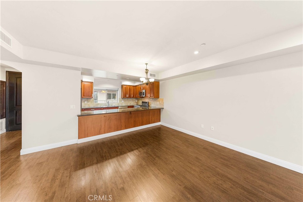 11218 Camarillo Street, Unit 404 Toluca Lake, CA 91602 - Photo 18 of 53 a view of kitchen and empty room with wooden floor