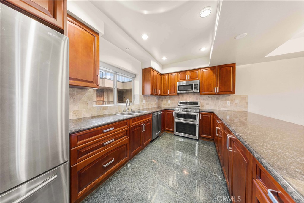 11218 Camarillo Street, Unit 404 Toluca Lake, CA 91602 - Photo 23 of 53 a kitchen with stainless steel appliances granite countertop a stove a sink and a refrigerator