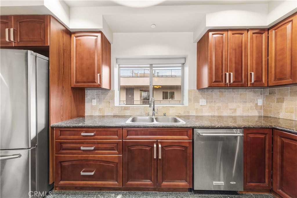 11218 Camarillo Street, Unit 404 Toluca Lake, CA 91602 - Photo 24 of 53 a kitchen with granite countertop a sink cabinets and stainless steel appliances