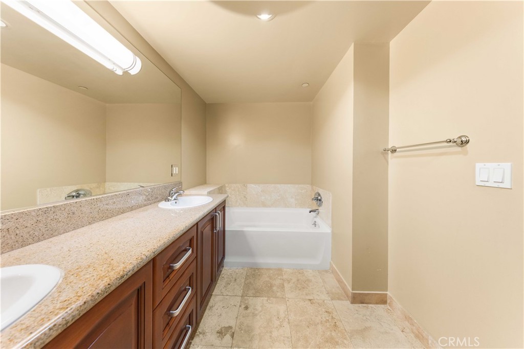 11218 Camarillo Street, Unit 404 Toluca Lake, CA 91602 - Photo 45 of 53 a bathroom with a granite countertop sink a mirror and a bathtub