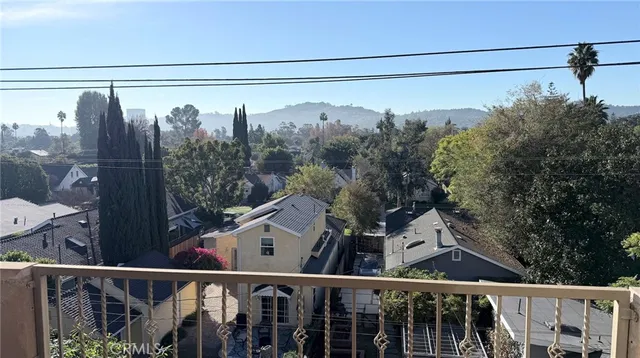 a living room with stainless steel appliances furniture large windows and wooden floor