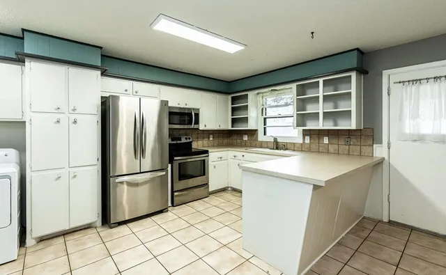 a kitchen with granite countertop a refrigerator stove top oven and sink