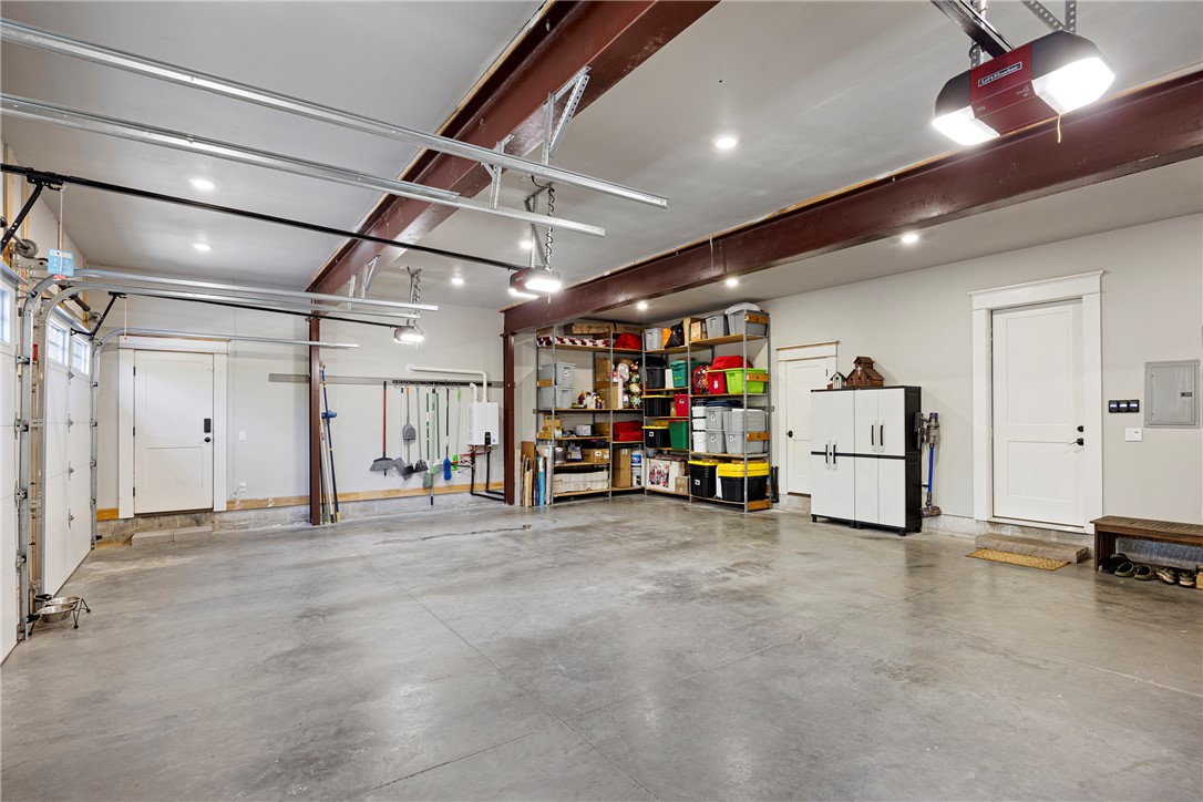 3419 Bailey Loop Road London, AR 72847 - Photo 46 of 60 Spacious garage featuring a concrete floor, exposed steel beams, multiple overhead lights, and an automatic garage door opener
