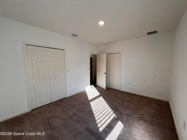 a view of an empty room with wooden floor and a bathroom
