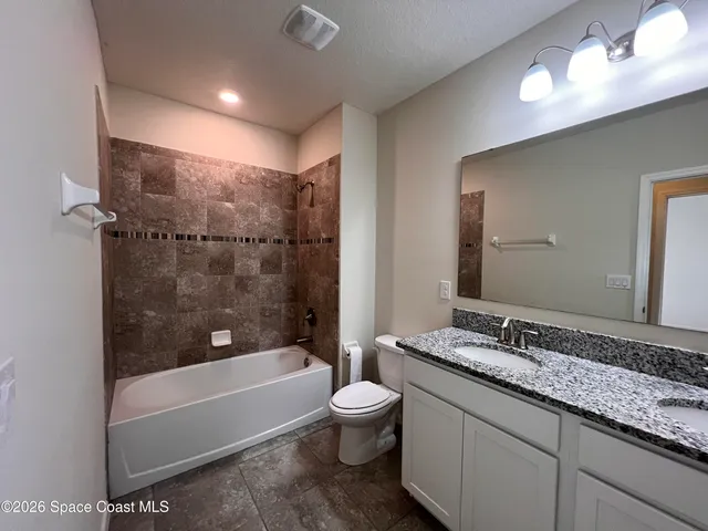 a bathroom with a granite countertop sink a toilet and bathtub