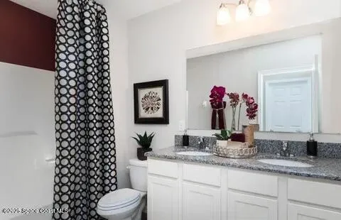 a bathroom with a granite countertop toilet a sink and a mirror