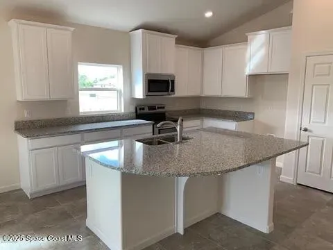 a kitchen with sink a microwave and cabinets