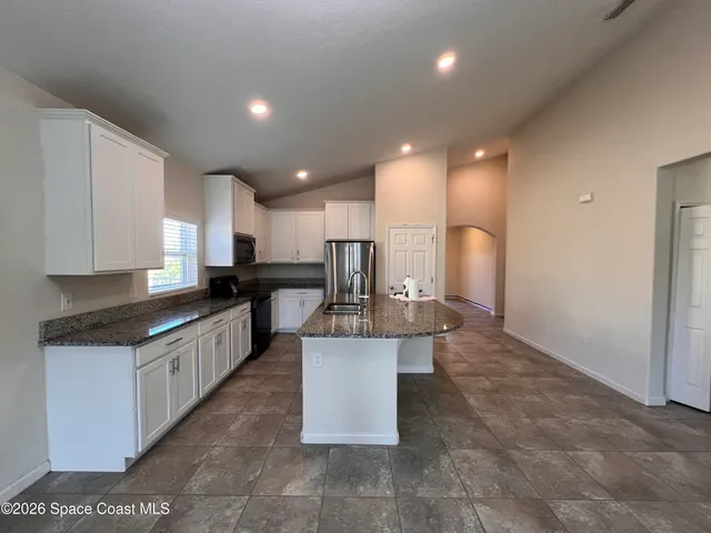 a large kitchen with kitchen island a sink a counter top space and stainless steel appliances