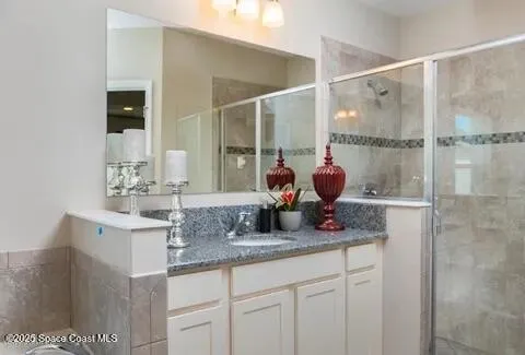 a bathroom with a granite countertop sink a mirror and shower