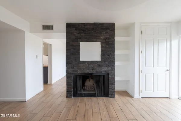 a view of empty room with wooden floor and fireplace