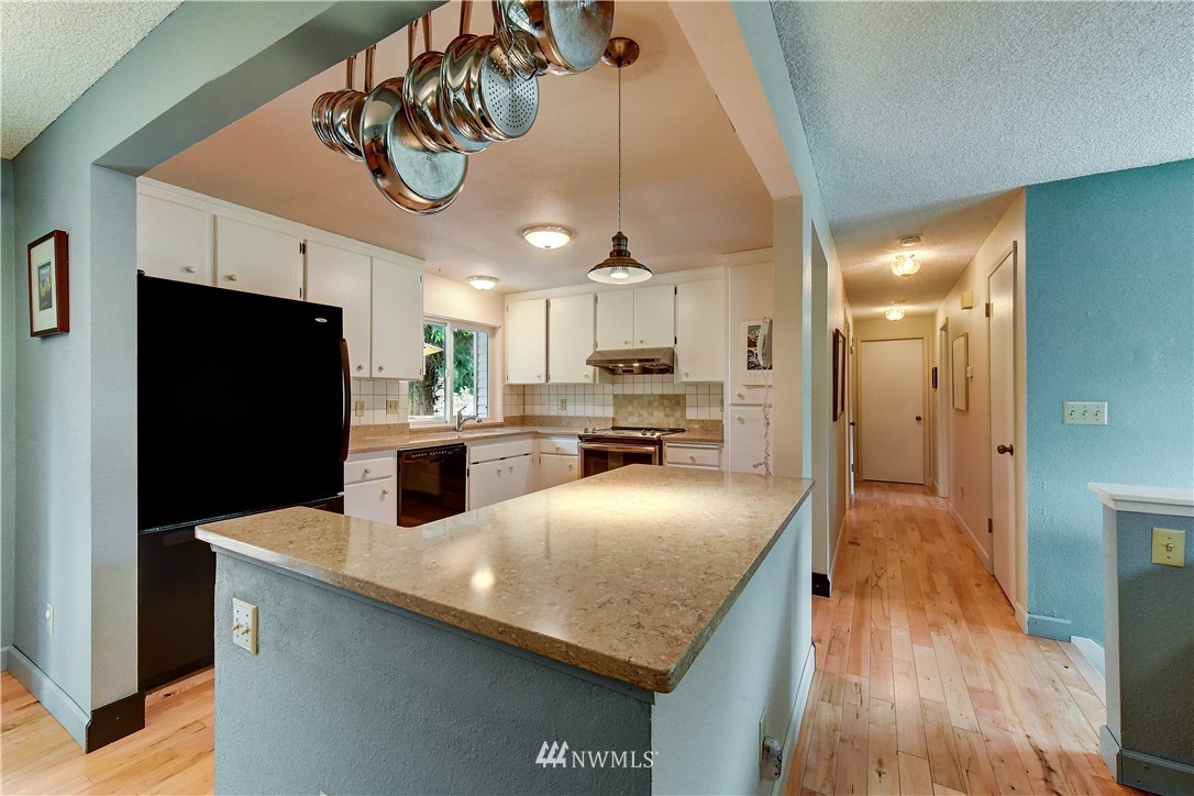 21616 9th Avenue West Bothell, WA 98021 - Photo 5 of 21 a kitchen with stainless steel appliances granite countertop a refrigerator a sink dishwasher a stove and a dining table with wooden floor