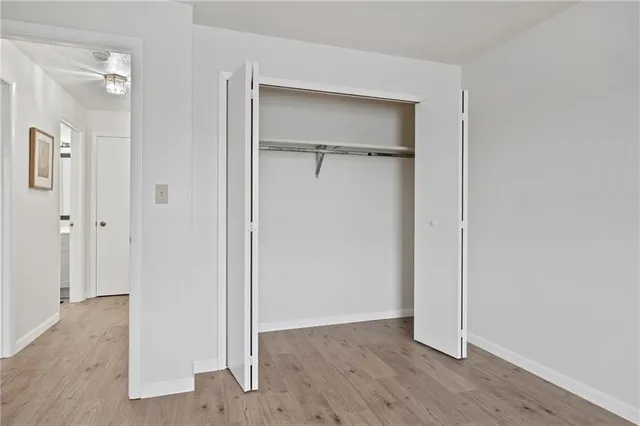 a view of an empty room with closet and wooden floor