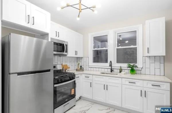 a kitchen with a refrigerator a sink stainless steel appliances and cabinets