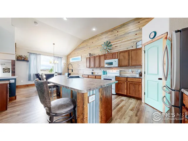 a living room with stainless steel appliances kitchen island granite countertop a table chairs and a refrigerator