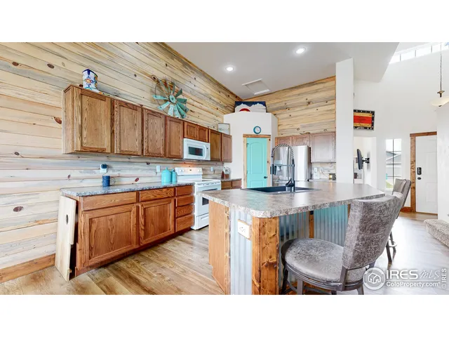a kitchen with stainless steel appliances kitchen island granite countertop a table chairs sink and cabinets