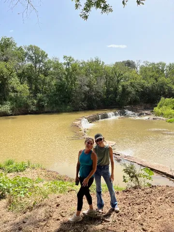 a view of a field with an ocean and trees in the background