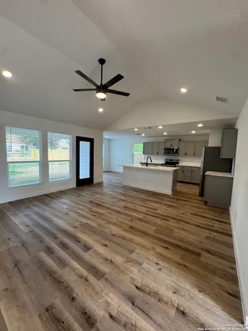 a view of an empty room with kitchen and window