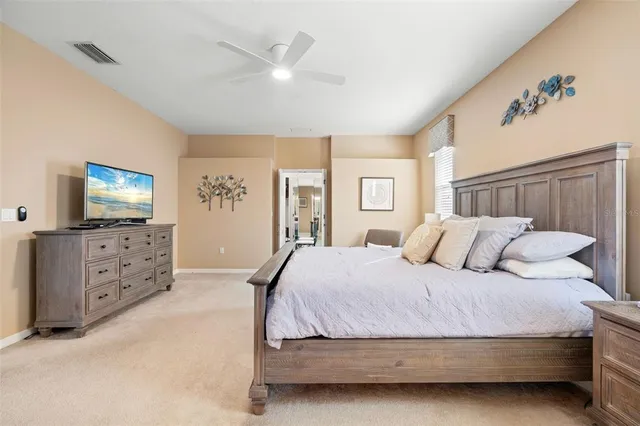 a bedroom with a large bed and a flat tv screen on dresser