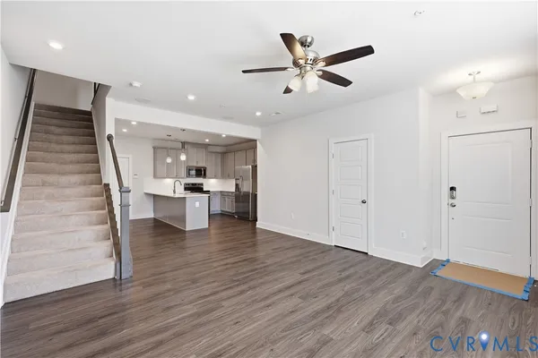 a view of an empty room with wooden floor and a ceiling fan